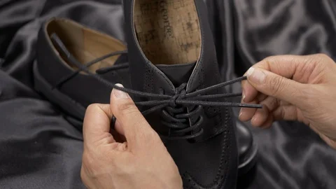 Close up - merchandiser lacing up a pair mans luxury dress shoe 4k. Stock Footage 96315397