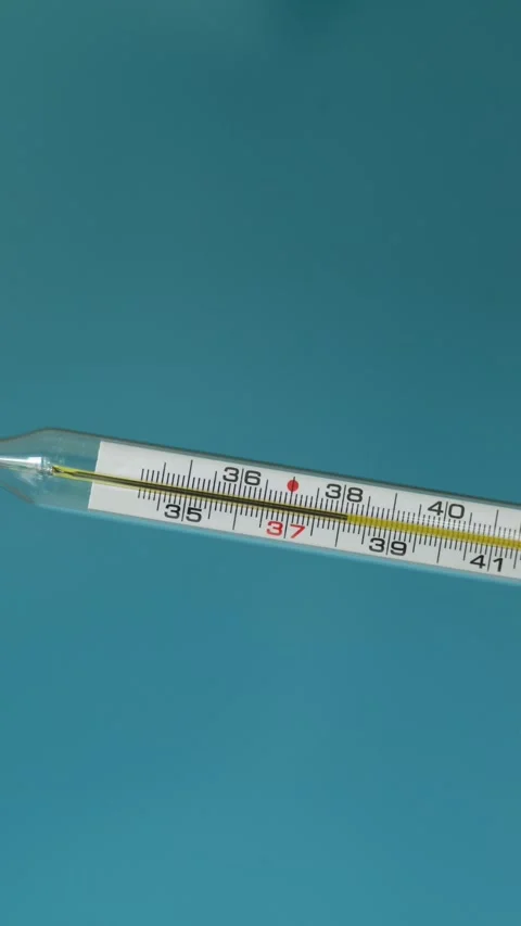 Close-up of a mercury thermometer showing temperature readings on a blue Stock Footage 340264405