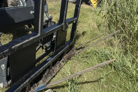 Close up of metal bale spear fork attachment on a farm tractor during agric.. Stock Photos