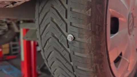 Close-Up of Metal Bolt Embedded in Car Tire Tread Stock Footage 343731392