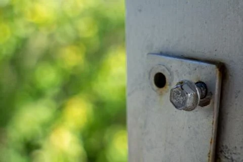Close-up of a metal bolt on a painted bracket with blurred green background Photos