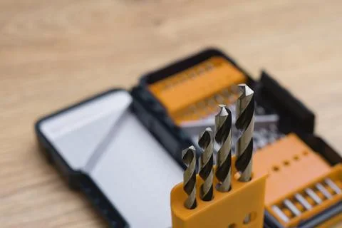 Close-up of a metal drill bit set organized in plastic case on wooden table.. Stock Photos