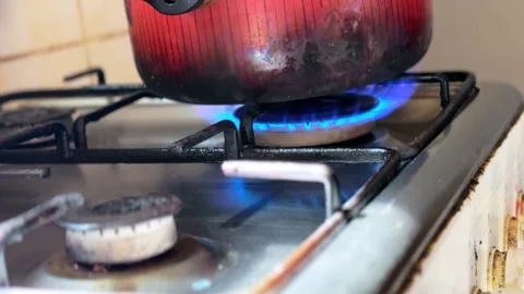 Close Up Metal Pot Heating Over Blue Gas Burner Flame on Indoor Kitchen Stove Stock Footage 332069444