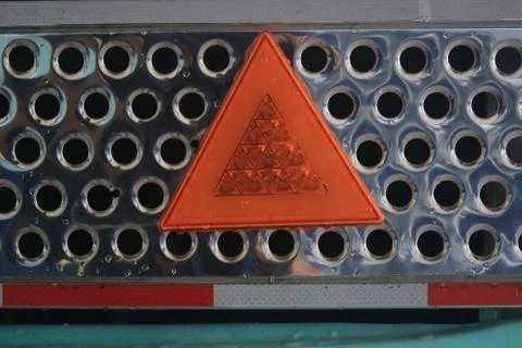 Close up of a metal shiny grid with a orange light reflecting warning triangle Stock Photos