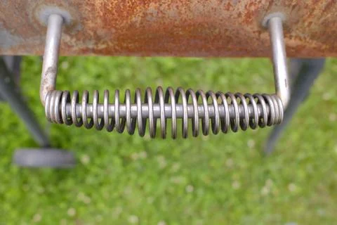 Close up of a metal spring handle attached to a rusty barbecue grill Photos