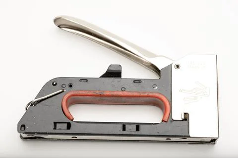 A close-up of a metal stapler with a red handle. The stapler is designed for Stock Photos