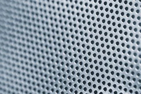 Close up of a metal surface with many small holes. The surface is silver and  Stock Photos