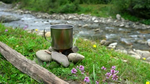 Close up of metal tea cup on fire near river.  Stock Footage 200669290