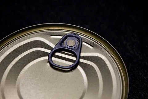 Close-up of metallic can lid with pull tab on dark background Fotos de archivo
