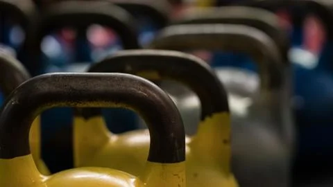 Close-up of metallic kettlebells of various weights and colors on the floor of a Stock Photos