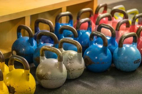Close-up of metallic kettlebells of various weights and colors on the floor of a Stock Photos
