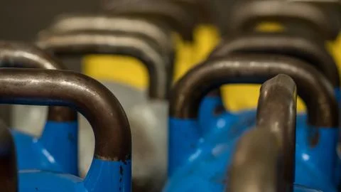 Close-up of metallic kettlebells of various weights and colors on the floor of a Stock Photos