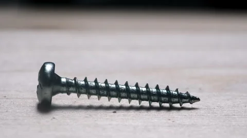 Close-up of a metallic screw lying on a wooden surface in a minimalistic en.. Stock Footage 309698533