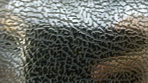 Close-up of a metallic surface with an abstract pattern. The reflective metal Stockfoto's
