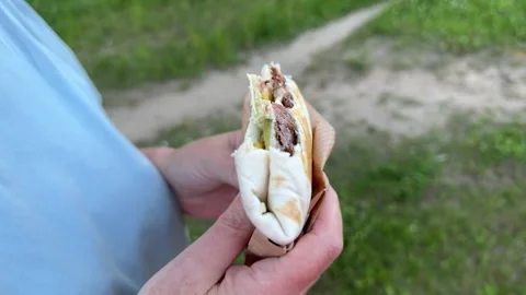 Close-up of a Mexican-style wrap with beef and vegetables held  Stock Footage 337774757
