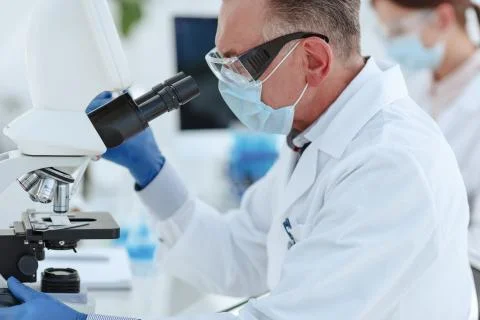 Close up. microbiologist a scientist looking through a microscope. Stock Photos