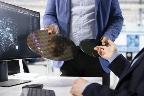 Close up of microchip designer inspecting silicon wafer substrates with AI Stock Photos