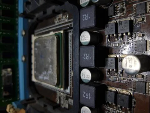 A close-up microchip with many electrical components placed on the Motherboard Stock Photos