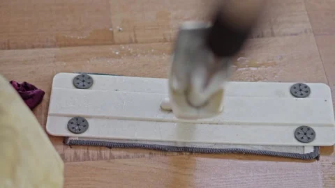 Close-up of microfiber mop head cleaning wet wooden laminate floor near orange Stock Footage 331325982