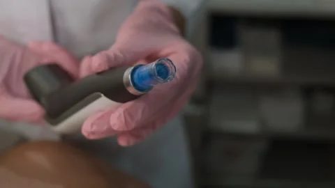 Close-up of a microneedling device held by a specialist wearing pink gloves Видео 325123513