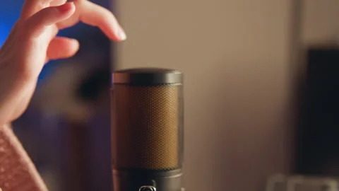 Close-up microphone resting on desk while hand approaches for careful adjustment Stock Footage 345655723