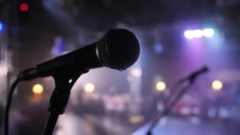 Close-up of microphone on stage against a black background with white lighting. Stock Footage 229556422