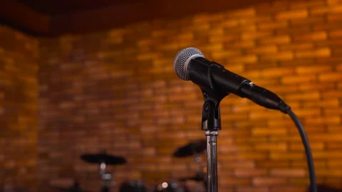 Close-up of microphone on stage against a orange background with white lighting Stock Footage 188527987