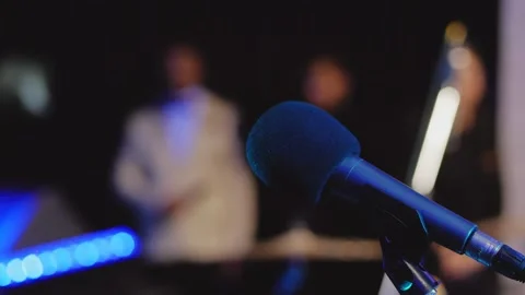 Close-up of a microphone on a stage with lighting and a blurry background. Stock Footage 169002298