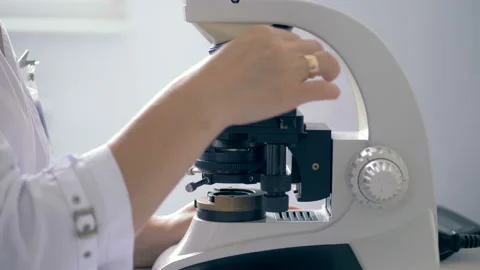 Close up of a microscope getting regulated by a lab worker Stock Footage 94659578