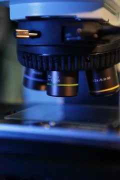 Close up of microscope lenses focused on a specimen in blue light Stock Photos