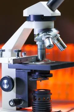 Close up of microscope lenses focused on a specimen in warm orange light light. Stock Photos