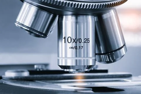 Close-up of microscope objective lens. Shiny metallic surface reflects light. Fotos de archivo