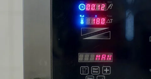 Close-up of microwave control panel with illuminated timers and status, with Stock Footage 344596363