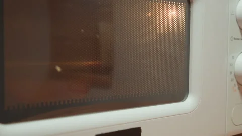 Close-up microwave door with perforated metal mesh and tinted glass revealing Stock Footage 345659416