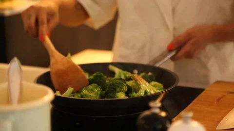 Close-up mid section view of a woman cooking broccoli in the frying pan Stock-Footage 114846838