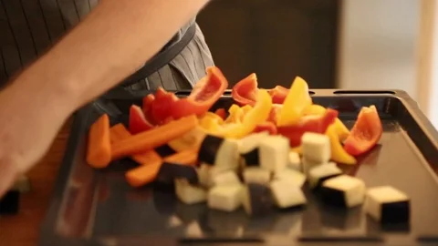 Close-up mid section view of a woman placing diced vegetables in the baking tray 스톡 동영상 114846843