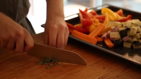 Close-up mid section view of a woman chopping rosemary at the kitchen counter Stock Footage 114846845