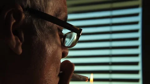 Close up of Middle age man lighting up a joint of marijuana in front of window, Stock Footage 45525392
