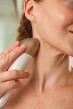 Close-up of middle aged lady doing led therapy neck skin care massage using a Foto stock