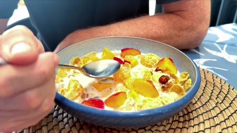 Close up of middle aged man at breakfast table eating bowl of cereal with fruit Stock Footage 340410144