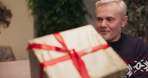 Close-up of middle-aged man exchanging gifts with son. The man smiles and Stock Footage 210591275