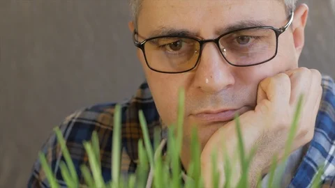 Close-up of a middle-aged man with glasses, leaning on his hand looking at the Stock Footage 106729547