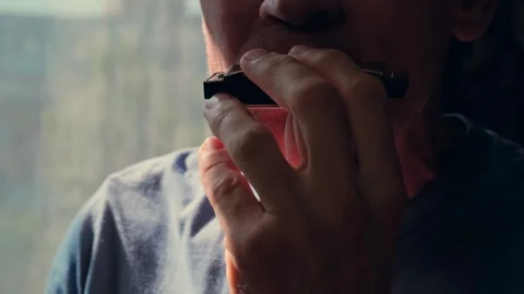 Close-up of a middle-aged man playing the harmonica at home. Stock Footage 340888820