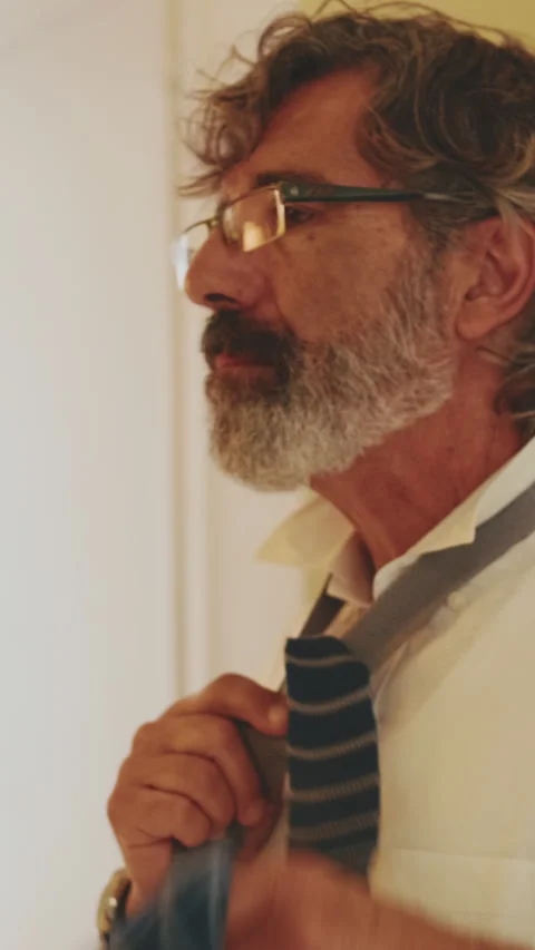 Close up, middle-aged man putting on tie while standing in front of mirror Stock Footage 229508361