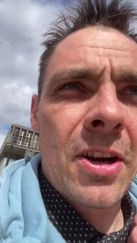 Close-up of middle-aged man speaking outdoors in light-blue jacket and patterned Stock Footage 341672385