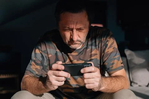 Close-up of a middle-aged man studying his phone with a tense, concentrated.. Stock Photos