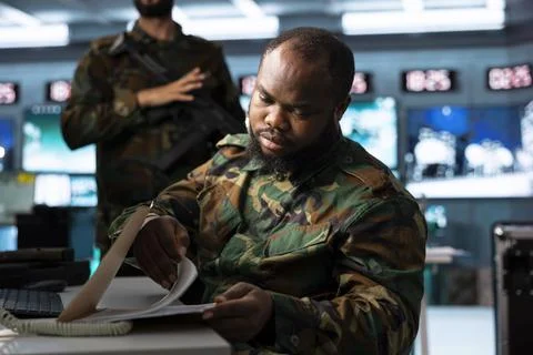 Close up of military analyst browsing documents at computer desk Stock Photos