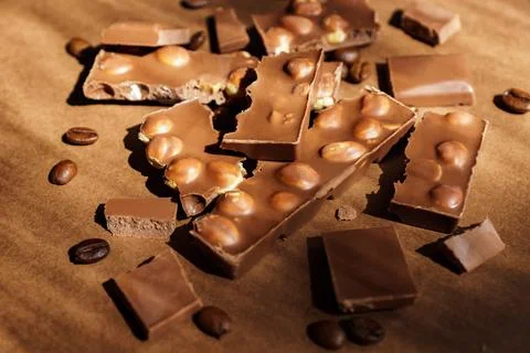 Close up of milk chocolate with hazel nuts on brown background. Sweet dessert Stock Photos
