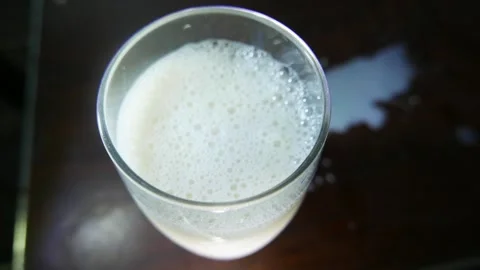 Close-up of a milk glass. Bubbles of milk rising in a glass. Milk on the table Stock Footage 330272058