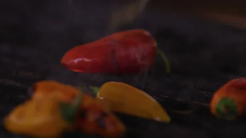 Close up mini bell peppers being flame grilled with flame and steam on grill top Stock Footage 203984778